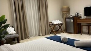 A hotel room with a bed, a desk, a chair, a television, and a small refrigerator. - The Nomad Pyramids Luxury Wing (Giza)
