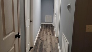 A narrow hallway with wooden flooring and white doors. - The Fields Master's Rental 2026 (Augusta)