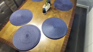 A dining table with four blue placemats, a potted plant, and a salt and pepper shaker. - The Fields Master's Rental 2026 (Augusta)