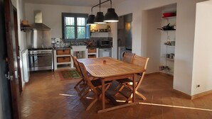 A modern kitchen with a dining area, featuring a wooden table and chairs, a stainless steel stove, and a large window. - Ancient cottage nestled in the heart of the Sicilian countryside just a few steps from the sea (Partinico)