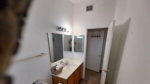 Ein Badezimmer mit Toilette, Waschbecken und Spiegel. Darüber befindet sich ein Handtuchhalter und eine Tür zu einem anderen Raum.