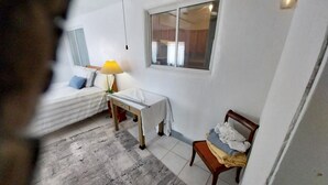 Ein Schlafzimmer mit Bett, Schreibtisch, Stuhl, Lampe und Fenster.
