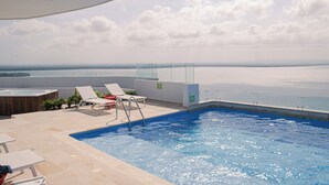 A rooftop pool with lounge chairs and a view of the sea. - Apartamento familiar en Cartagena, cerca al aeropuerto y playa Las Americas (cartagena de indias)