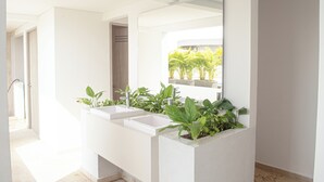 A modern bathroom with three white sinks, a large mirror, and potted plants. - Apartamento familiar en Cartagena, cerca al aeropuerto y playa Las Americas (cartagena de indias)