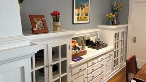 A room with a white cabinet with glass doors, a framed picture on top, and a framed poster on the wall. - Beautiful Craftsman Home in Terrific Hollywood Neighborhood (Los Angeles)