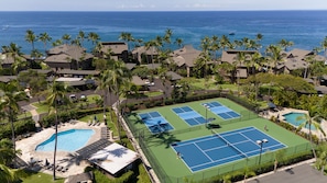 Un resort con múltiples canchas de tenis, una piscina y vista al océano.