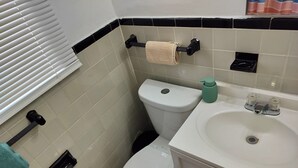 Kylpyhuone, jossa on wc, pesuallas ja pyyheteline.