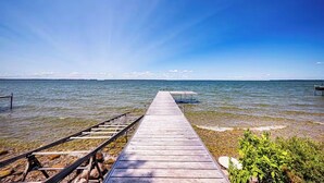 Eine Holzstege, der in ruhiges Wasser führt, ein klarer Himmel und entferntes Land.