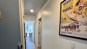 Een gang met een poster van Elvis Presley aan de muur, een deur met een cijfercode slot en een lichtschakelaar.