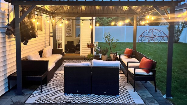 Un'area patio coperta con posti a sedere e luci a tendina.