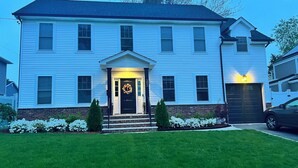 Una casa a due piani con un portico, una porta d'ingresso nera decorata con una ghirlanda e un basculante del garage.