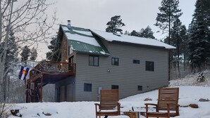 Een huis met twee verdiepingen, een metalen dak en een houten terras.