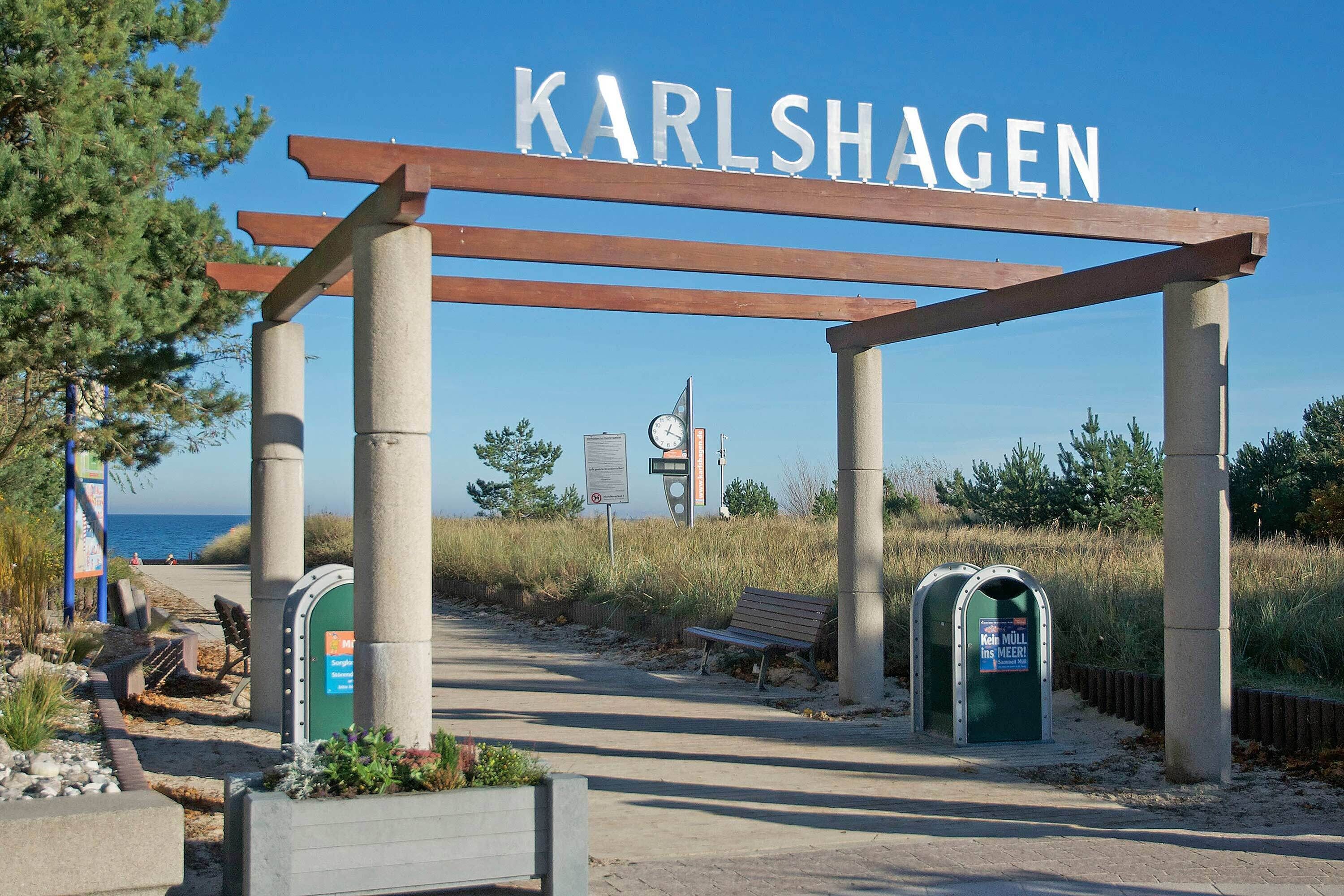 A sign reading 'KARLSHAGEN' above a pathway leading to a beach.