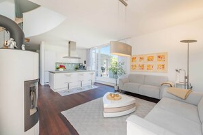 A modern living room with a sofa, a coffee table, and a kitchen area with a bar stool. - Exclusive penthouse in Karlshagen - sauna, fireplace & close to the beach (Karlshagen)