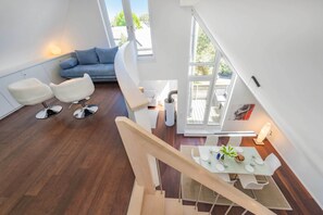 A modern interior with a dining area, a sofa, and a staircase. - Exclusive penthouse in Karlshagen - sauna, fireplace & close to the beach (Karlshagen)