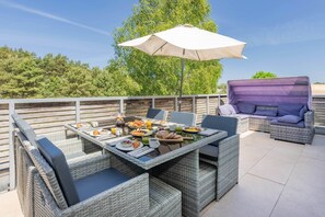 A patio with wicker furniture, a table set with food, and a grill. - Exclusive penthouse in Karlshagen - sauna, fireplace & close to the beach (Karlshagen)