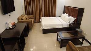 Ein Hotelzimmer mit einem Bett, einem Schreibtisch, einem Sessel, einem kleinen Tisch und einem an der Wand befestigten Fernseher.
