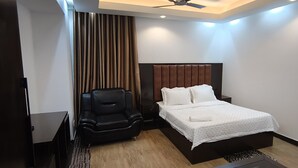 Ein modernes Hotelzimmer mit einem Bett, einem schwarzen Ledersessel und einem Deckenventilator.