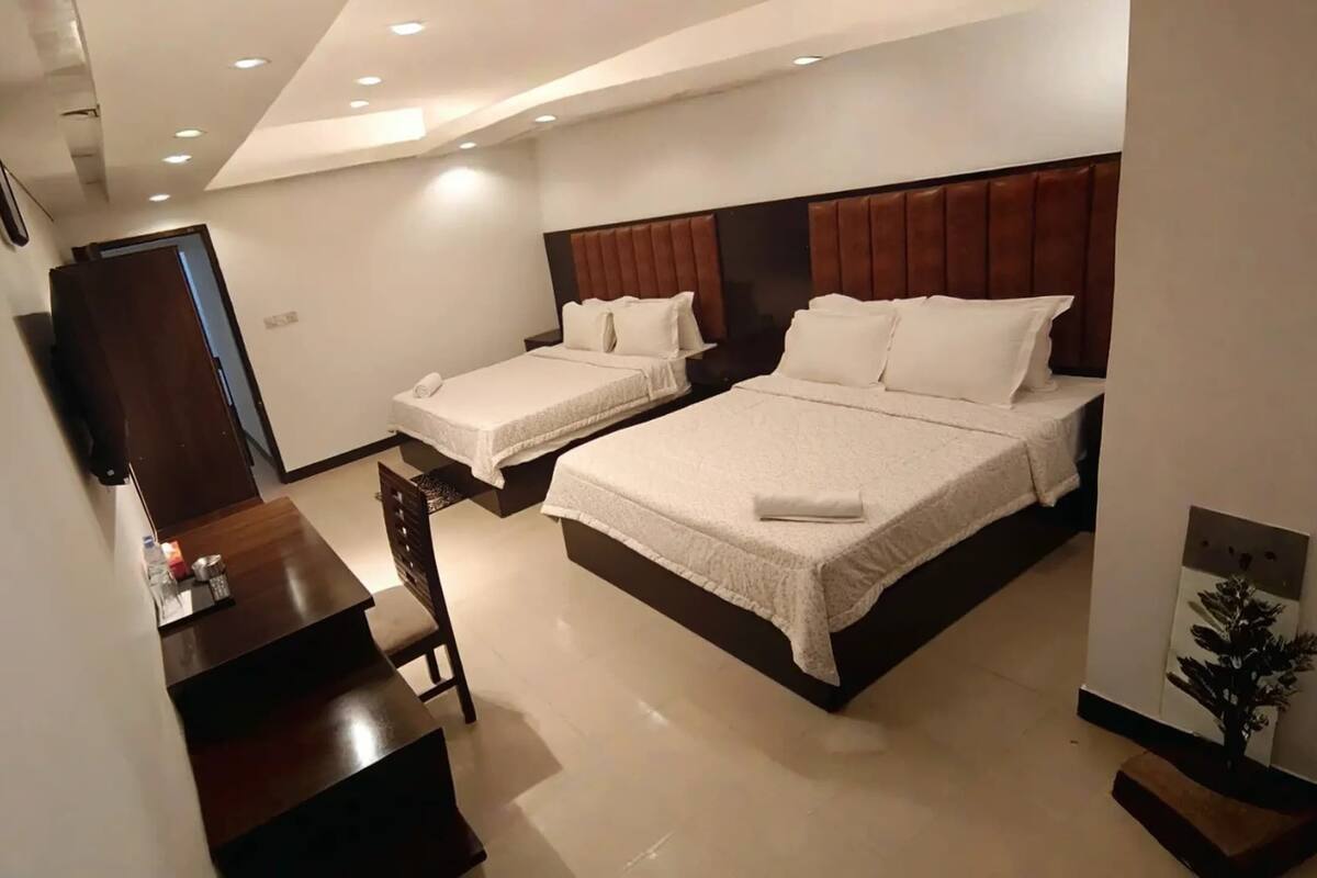 Une chambre d’hôtel avec deux lits, un bureau et une chaise.