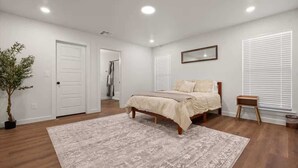 A bedroom with a bed, a nightstand, a potted plant, and a window with blinds. - Langford House - 3BR/2BA - Family Friendly (Lubbock)