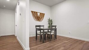 A dining area with a table and chairs, a wall-mounted decorative piece, and a potted plant. - Langford House - 3BR/2BA - Family Friendly (Lubbock)