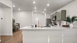 A modern kitchen with white cabinetry, a granite countertop, and recessed lighting. - Langford House - 3BR/2BA - Family Friendly (Lubbock)