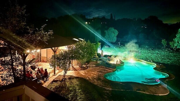 Uma área de piscina ao ar livre à noite, com espaço para sentar e um elemento aquático.
