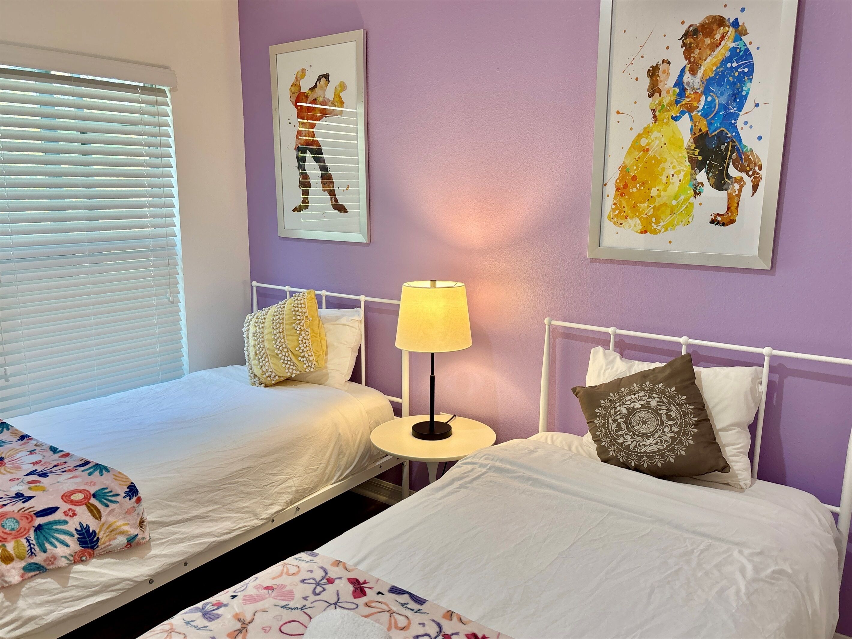 Une chambre avec deux lits, une table de chevet avec une lampe et des œuvres d’art accrochées aux murs.
