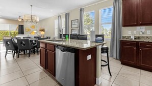 A modern kitchen with a central island, dark wooden cabinets, and a built-in dishwasher. - 7601 Luxury 7BR Themed Villa w/ Private Pool & Spa (Kissimmee)