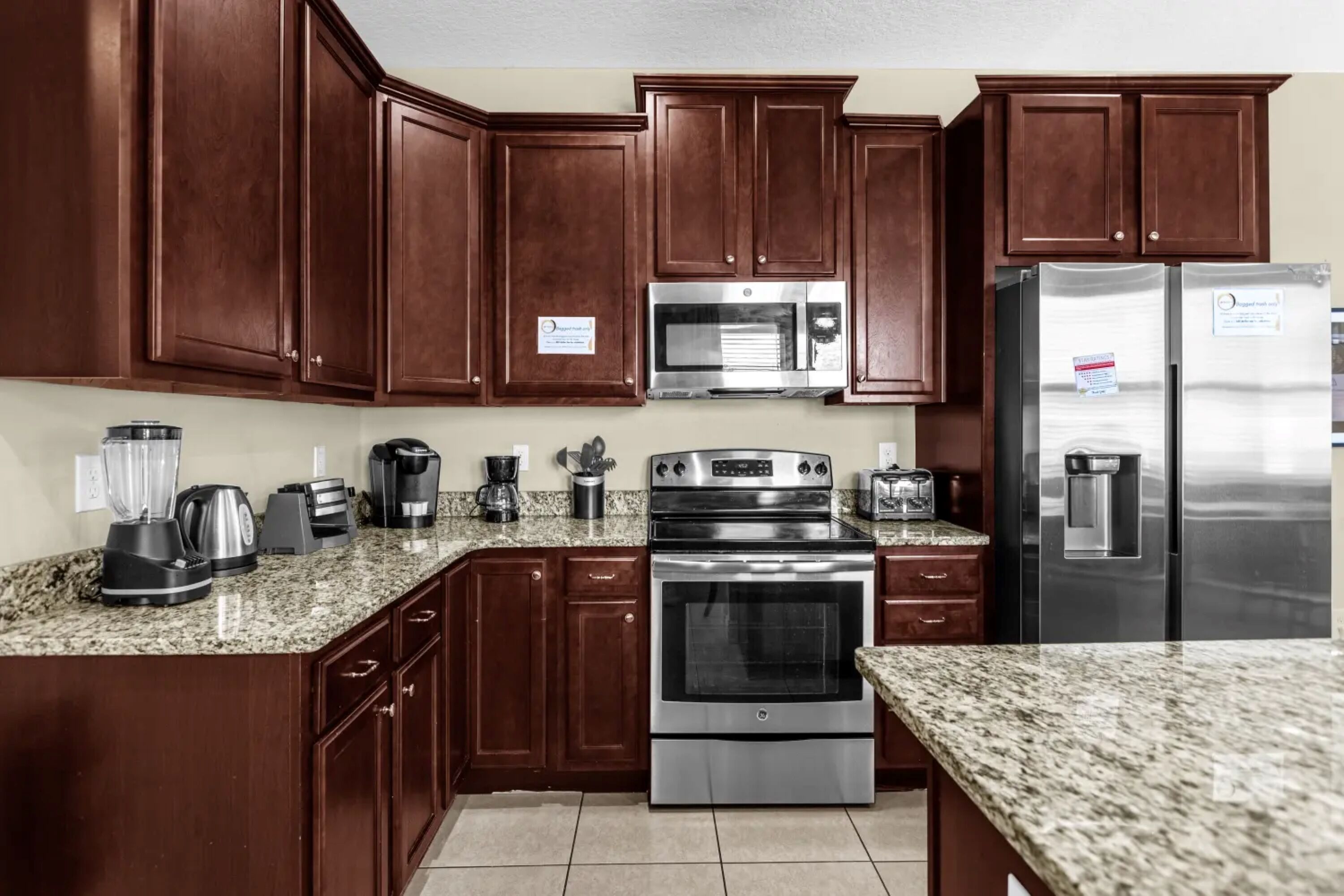 A kitchen with dark wooden cabinets, stainless steel appliances, granite countertops, and a built-in oven.