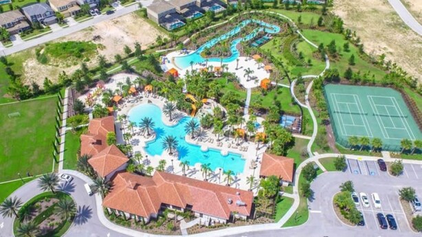 An aerial view of a resort with a central swimming pool, tennis courts, and a parking area. - 7BR Resort Pool Home Near Disney - 8004 (Davenport)