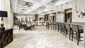 A spacious kitchen with a long counter and multiple chairs, a ceiling fan, and a modern light fixture. - 7BR Resort Pool Home Near Disney - 8004 (Davenport)