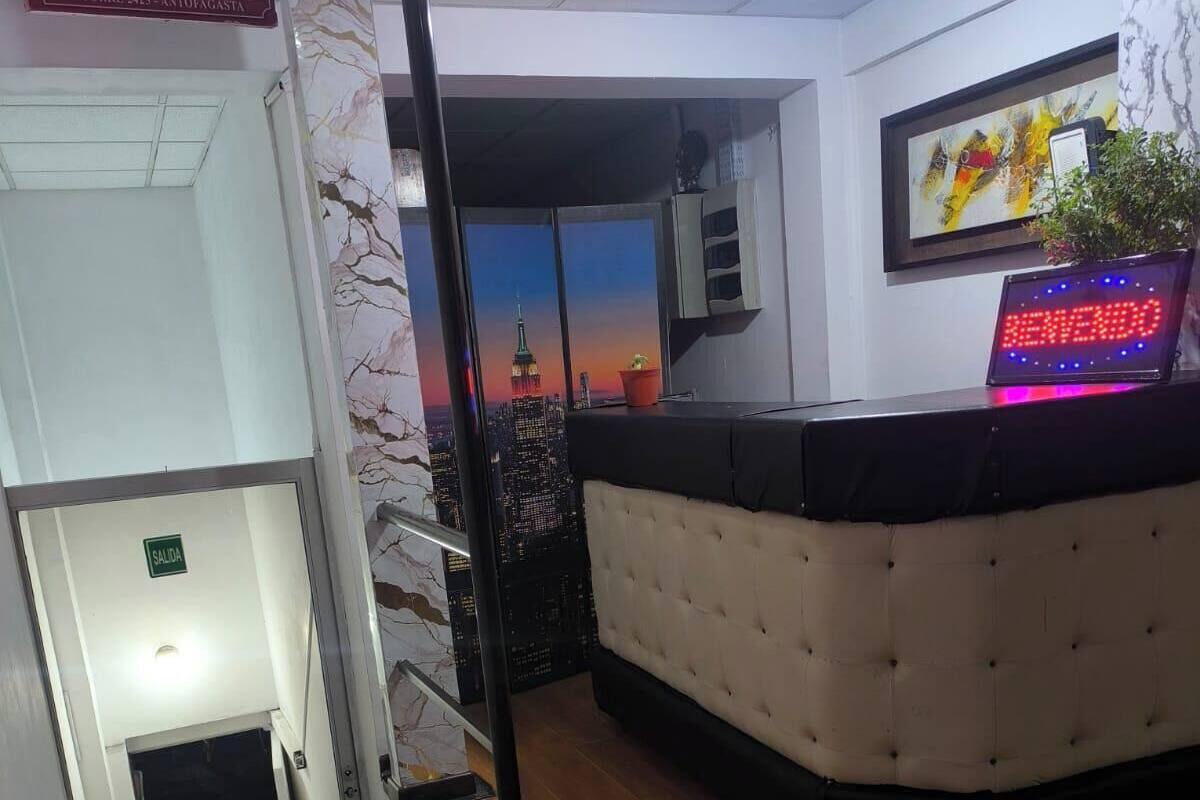 Ein Hotel-Empfangsbereich mit einer Rezeption, einem Schild für das Hotel Dakota, Blick auf das Empire State Building und einer Treppe, die in einen anderen Bereich führt.