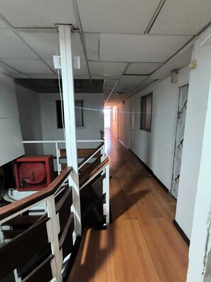 A corridor with wooden flooring, white walls, and a red object on the left. - Hotel Dakota  (Antofagasta)