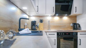 Een moderne keuken met witte kasten, een inbouwoven, een koffiezetapparaat en een messenblok.
