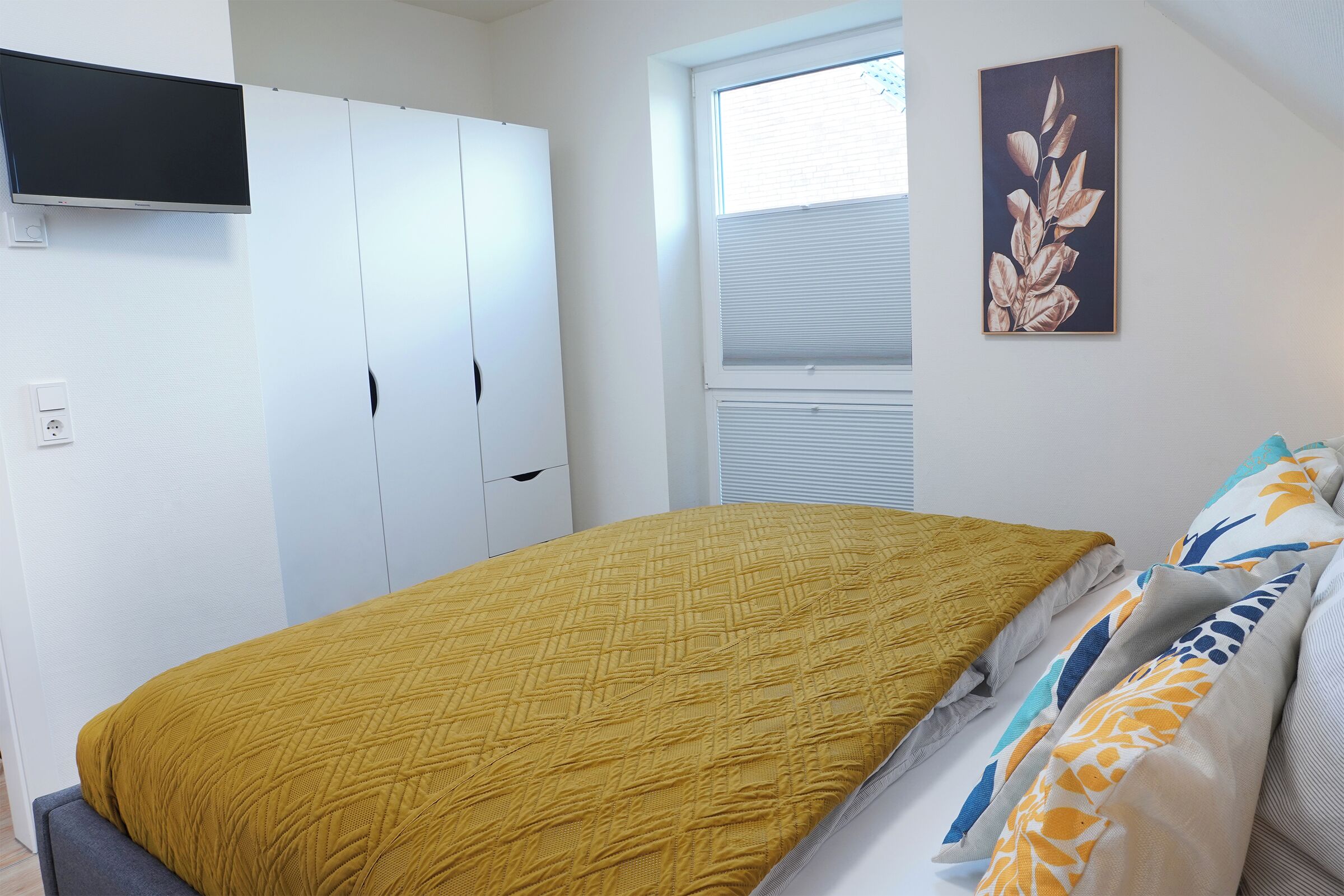 Una camera da letto con un letto, un armadio, una finestra e un'opera d'arte appesa al muro.