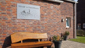 Un banc en bois se trouve à l’extérieur d’un bâtiment sur lequel est apposée une enseigne indiquant « Stindt’s Deichhues ».