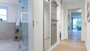 A modern interior with a glass partition, wooden flooring, and a view into another room. - Seestraße 8/13 - Modern. Close to the beach. Sauna. Balcony. (Kellenhusen)