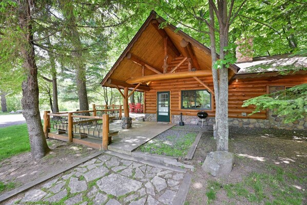 Eine Holzhütte mit Veranda, Steinstufen und Grillplatz außen.