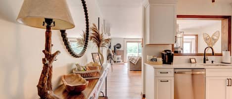 A kitchen with white cabinets, a wooden countertop, and a large window.
