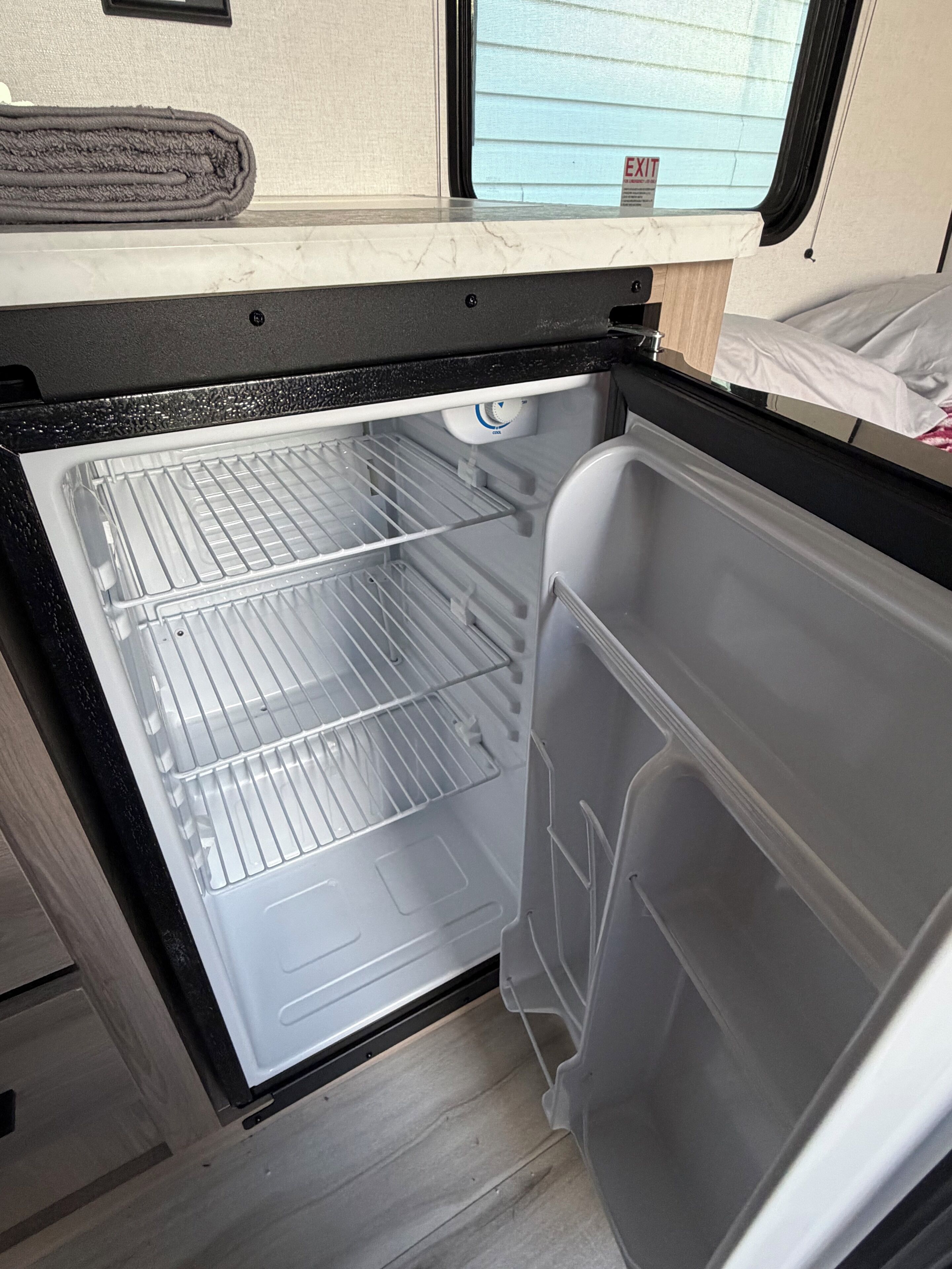 A compact refrigerator with a freezer compartment, a control panel, and a transparent door.