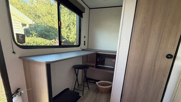 A compact kitchenette with a microwave, a sink, and a small bar stool.