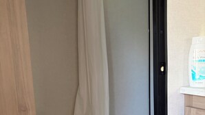 A small, compact bathroom with a toilet, a shower area, and a white cabinet.