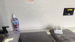 A kitchen counter with a black induction cooktop, a bottle of hand soap, a folded towel, and a power outlet.