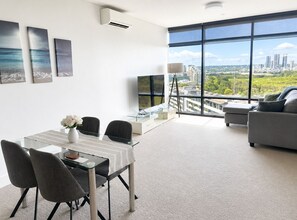 Una sala de estar moderna con un ventanal grande, un comedor con mesa de vidrio y un sofá.