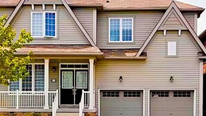 A two-story house with a front porch, two garage doors, and a small front yard. - Lola's Place Luxury 4BR with 4BEDS  Close to fall, sleeps 8... (Welland)