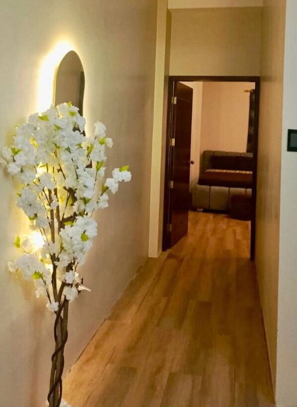 A hallway with a wooden floor, a white flower arrangement, and a piano in the background. - CABALLITO DE MAR (Puerto Baquerizo Moreno)