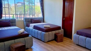 A room with three beds arranged in a row, each with a pillow and a rolled towel.