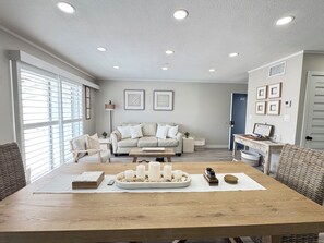 A modern living room with a sofa, coffee table, and a dining table with candles. - SAND & SEA BEACH RETREAT  (New Smyrna Beach)
