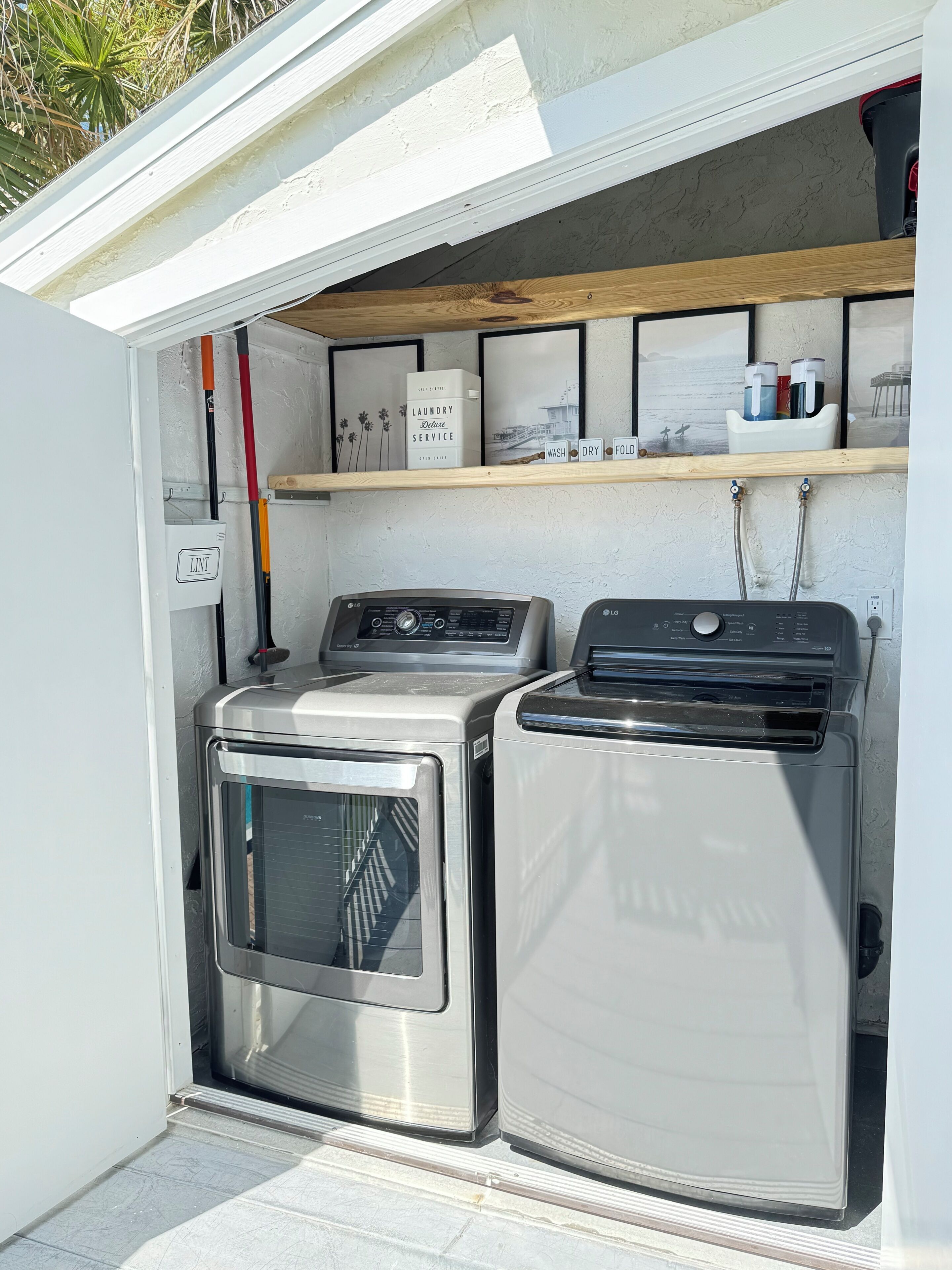 Een kleine wasruimte met een wasmachine, droger en een plank met een waterdispenser en een bordje dat dienstverlening voor wasgoed aangeeft.